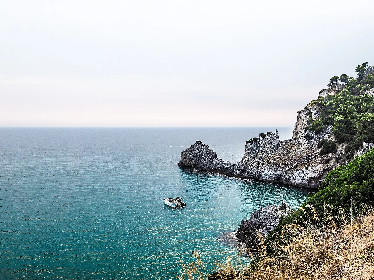 Rocky Amalfi coastline and a boat on turquoise Mediterranean water
